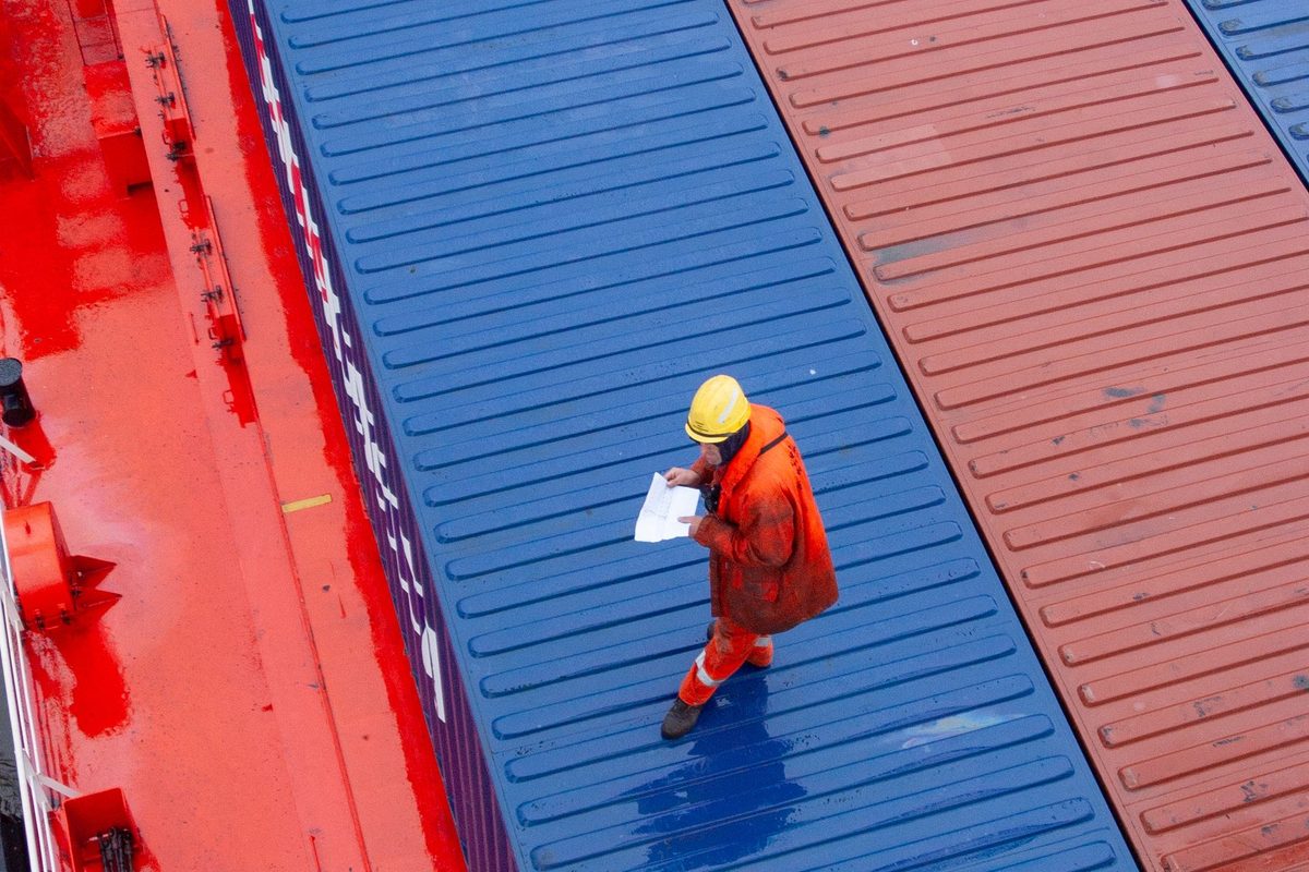 A port worker inspecting stacked freight containers